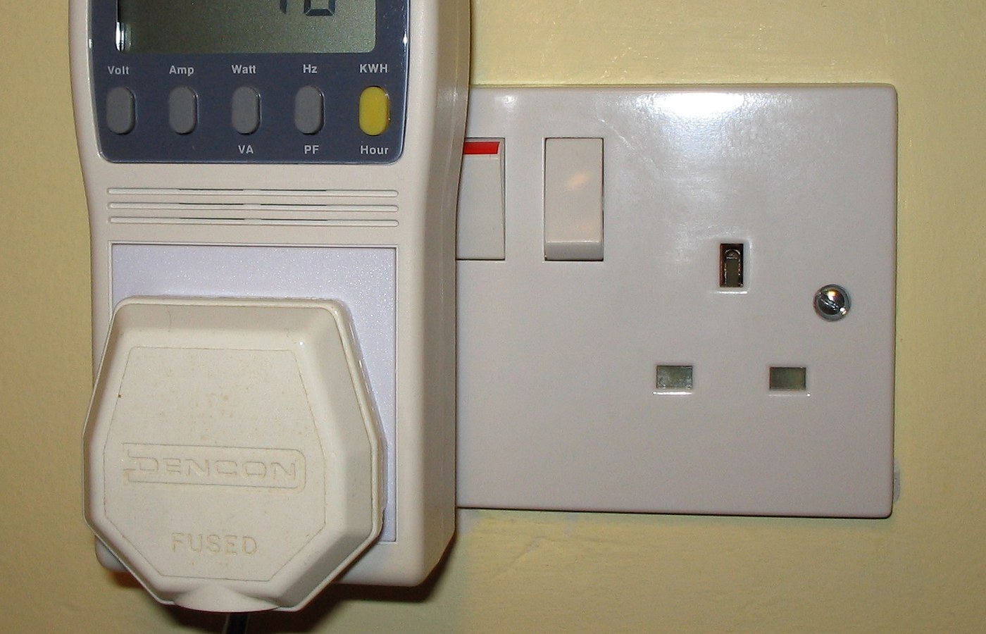 Real photo of plug-in power and energy monitor in uk domestic mains socket for Energy monitor vs smart meter in-home display