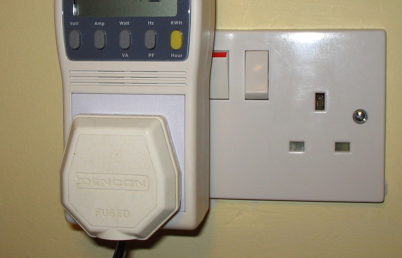 Real photo of plug-in power and energy monitor in uk domestic mains socket for Energy monitor vs smart meter in-home display